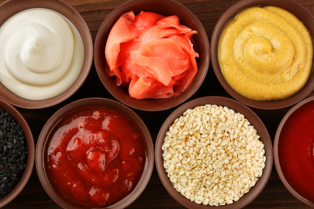 Fresh condiments and sauces on wooden background, closeup