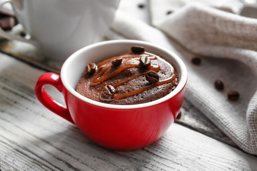 Cup with tasty chocolate brownie on white wooden background