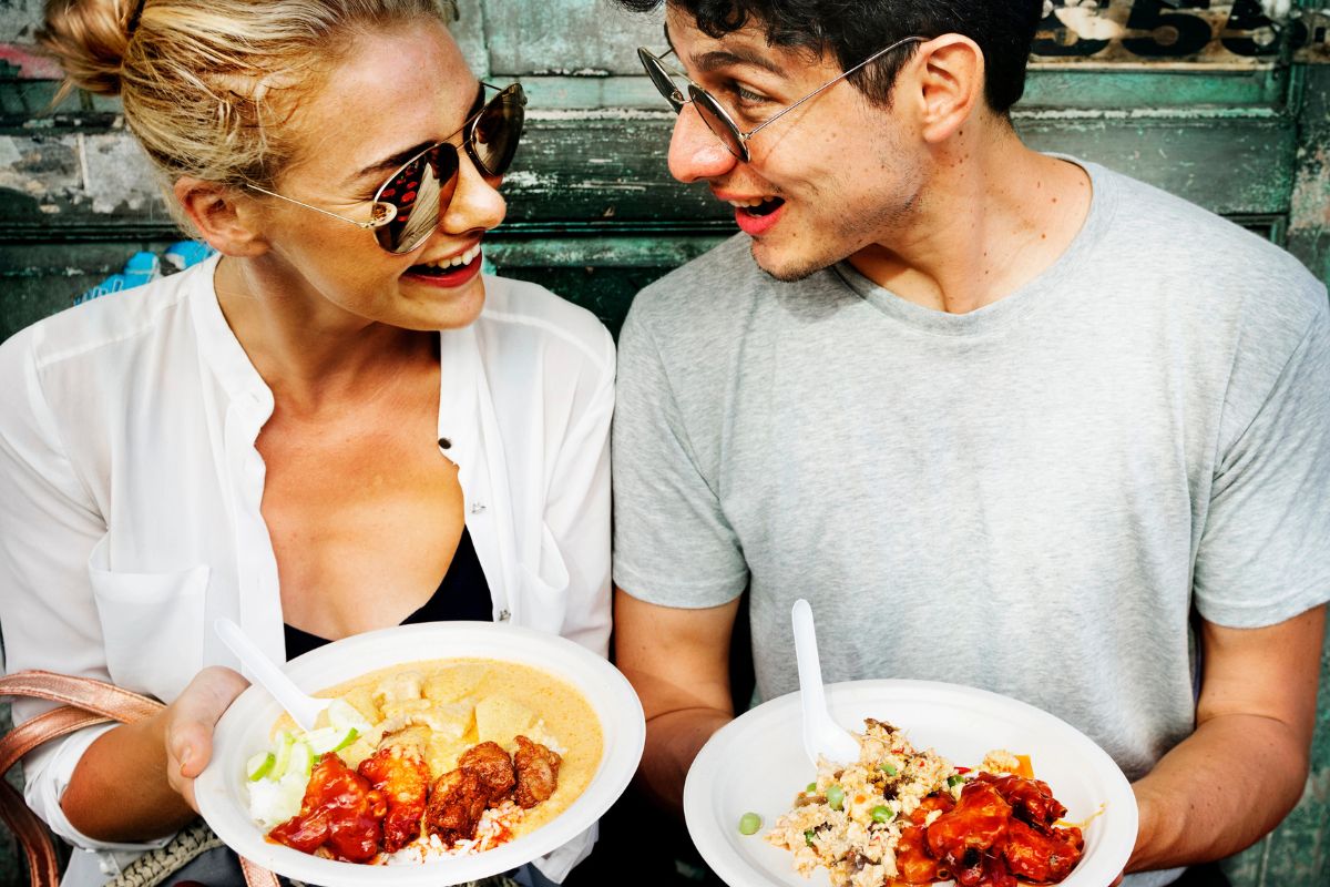 Man and a woman holding bowls of asian food