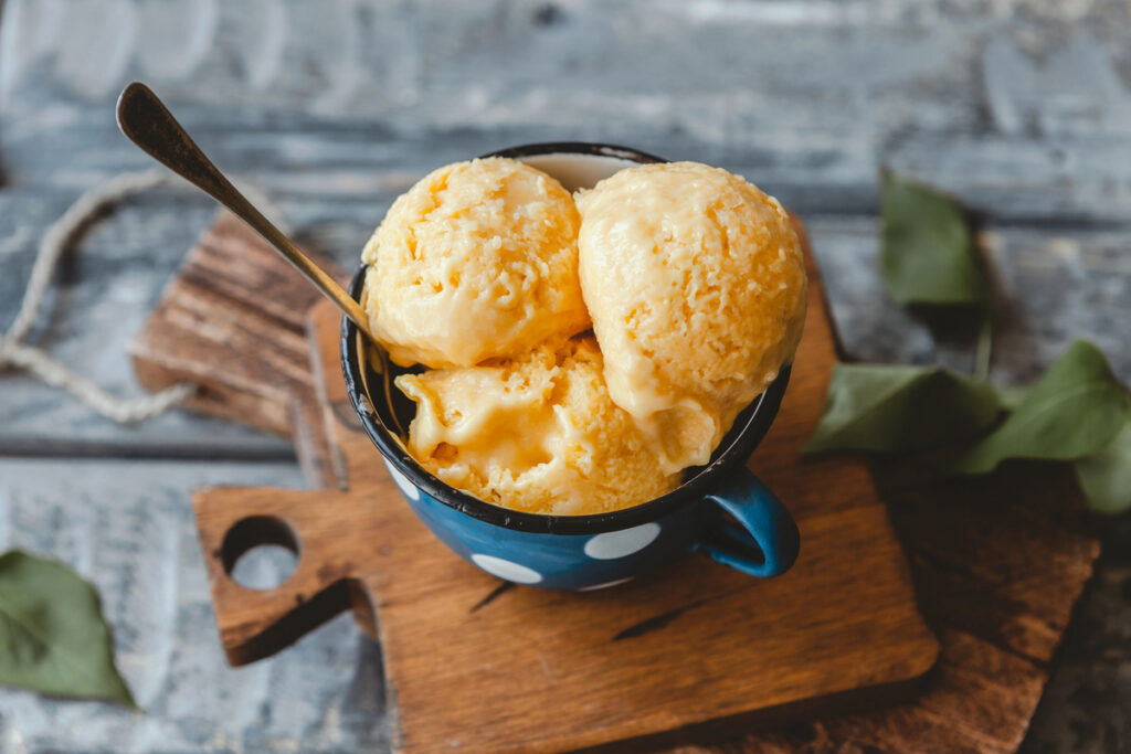 Fresh mango sorbet in blue metal mug with spoon