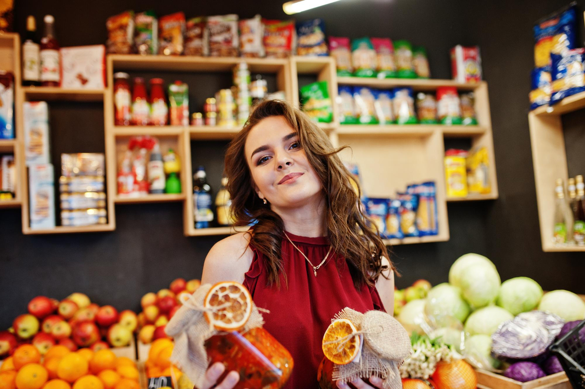 Girl in red holding jam in a jar on fruits store