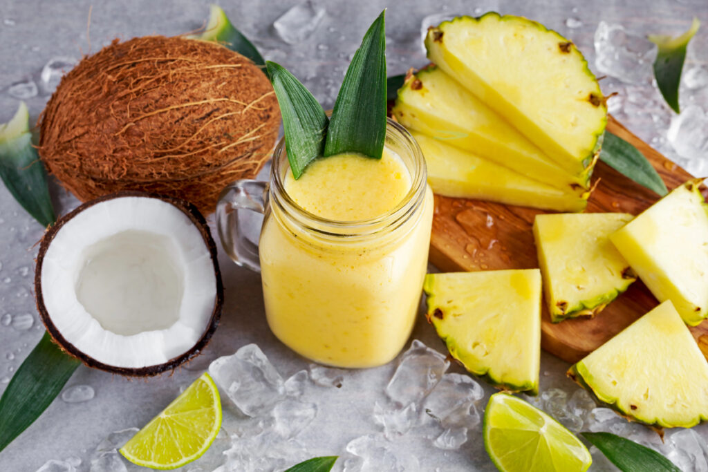 Healthy ripe Yellow Pineapple, coconut, Smoothie with slices of Lime and ice.