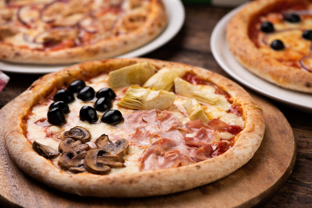 Pizza Four Seasons on wooden table close up