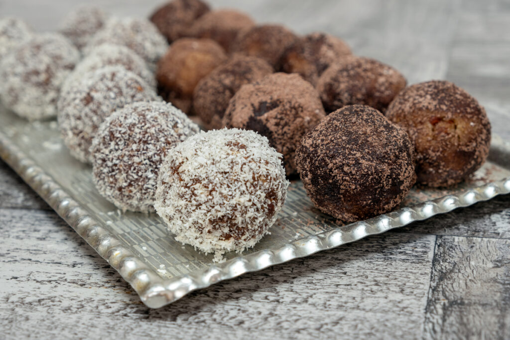 Coconut rum balls being covered with grated coconut