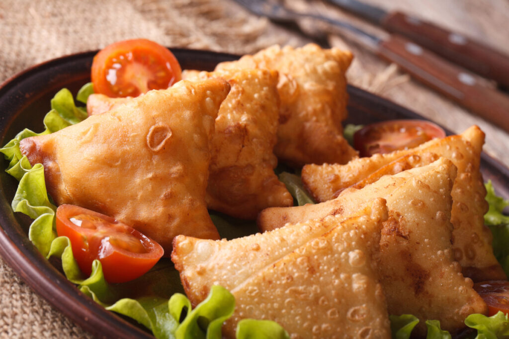 Samosa with lettuce on a wooden table.