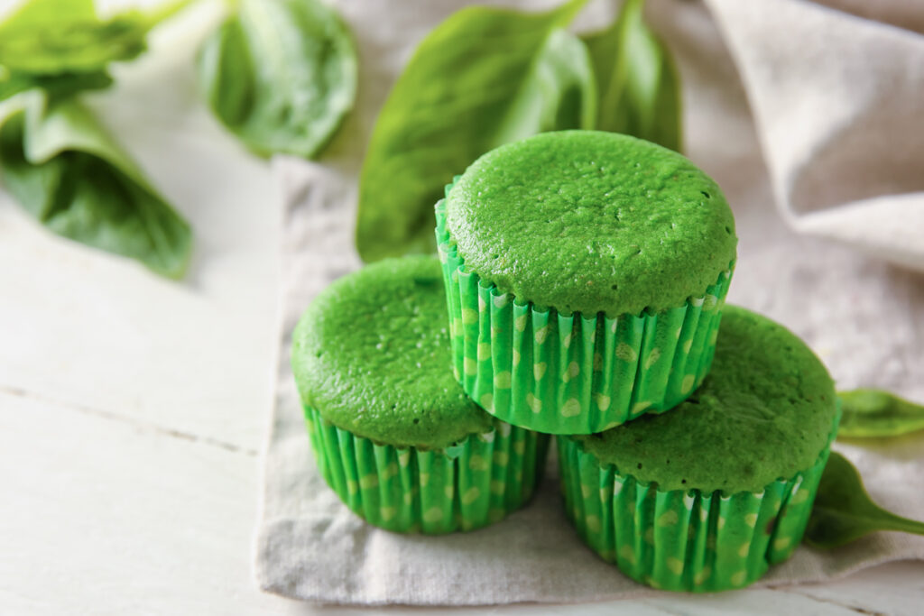 Tasty spinach muffins on light wooden background