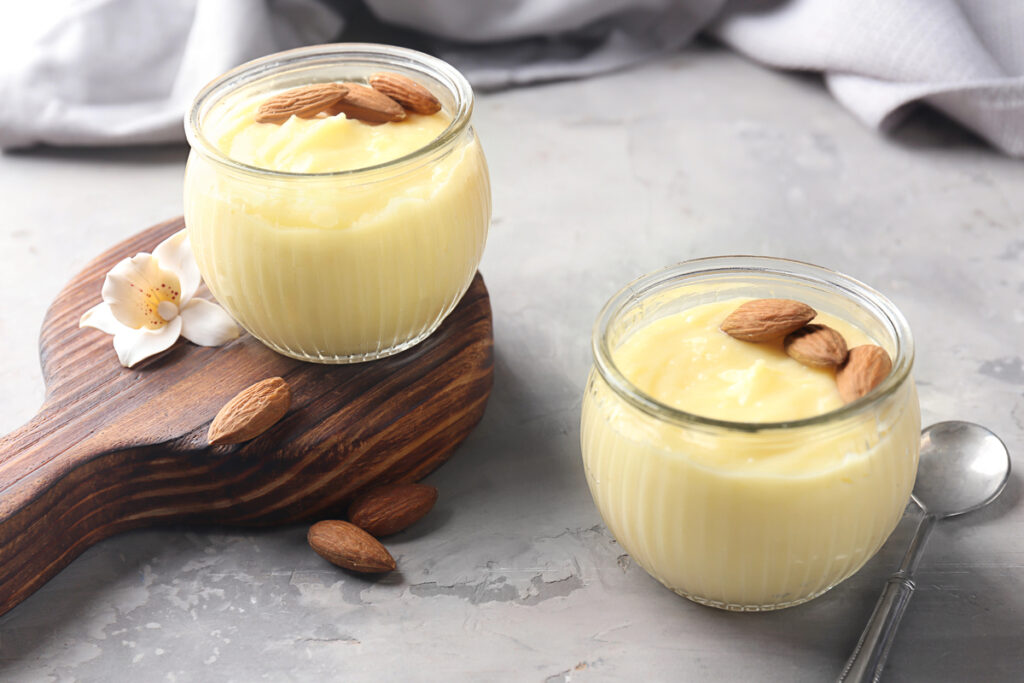 Glass jars with vanilla pudding with almond on table