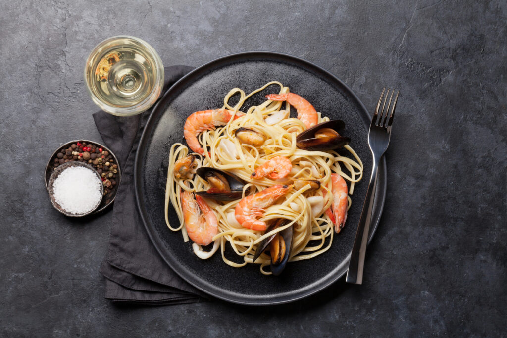 Spaghetti seafood pasta with clams and prawns. White wine glass. Top view with copy space. Flat lay