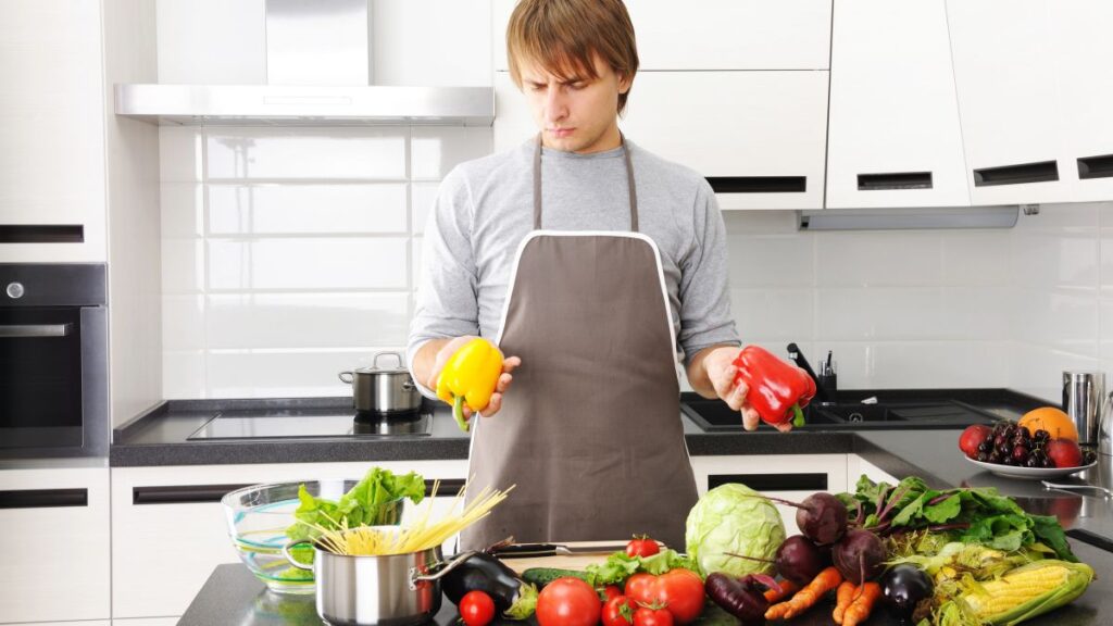 confused man in kitchen with vegetables