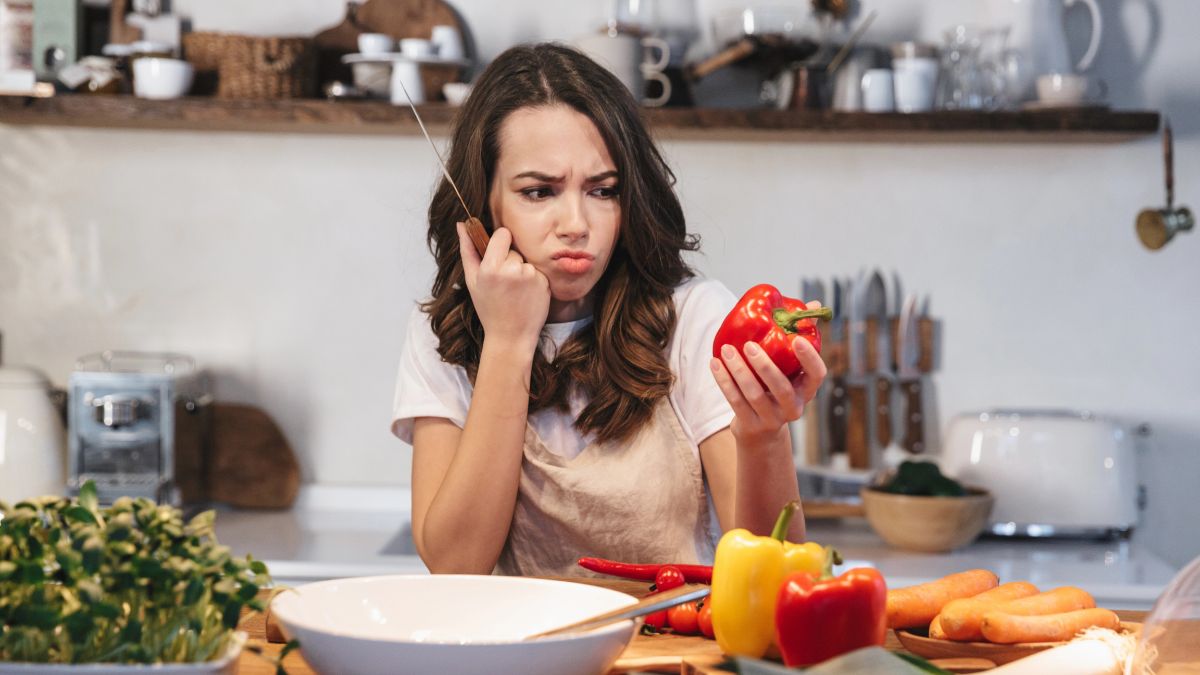 confused woman looking at pepper in kitchen