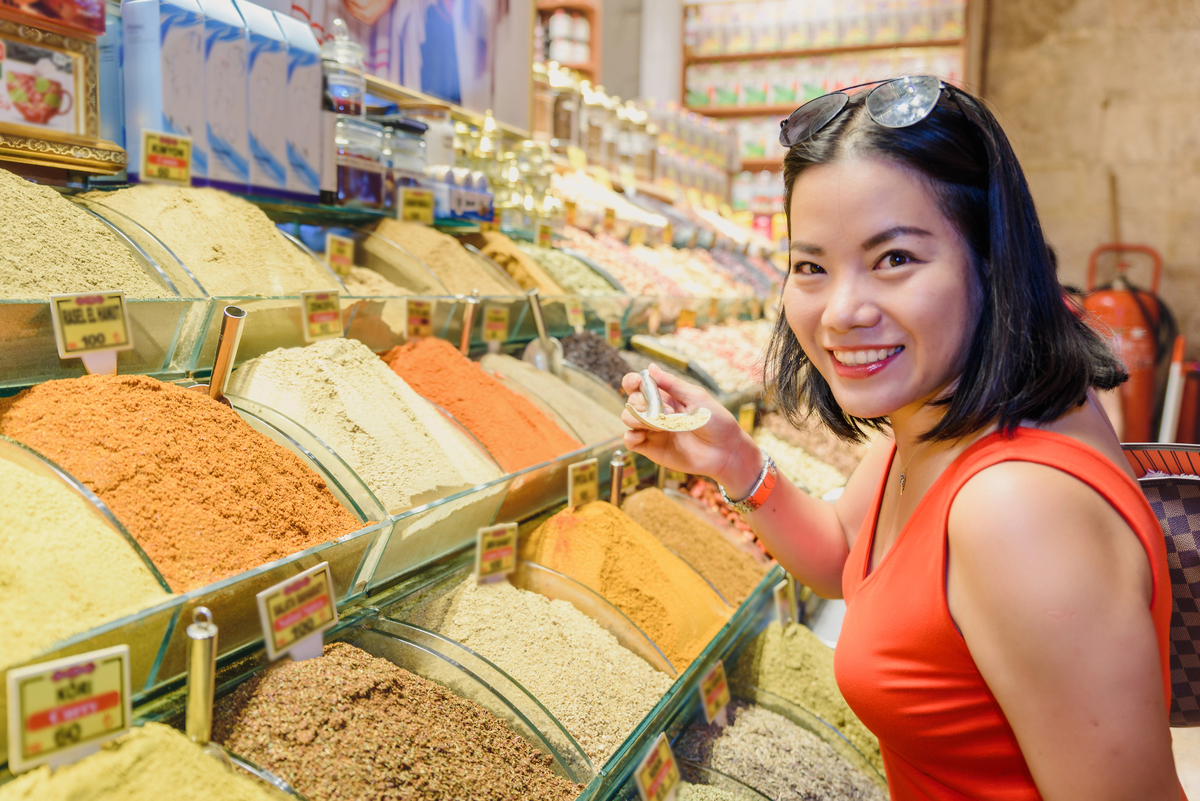 Beautiful woman smells different kind of spices sold on stall