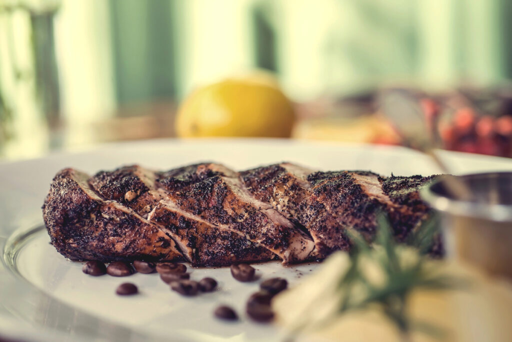 Delicious beef steak with tomato sauce, melon and rosemary, decorated coffee beans on the plate, wooden table. autumn concept. 