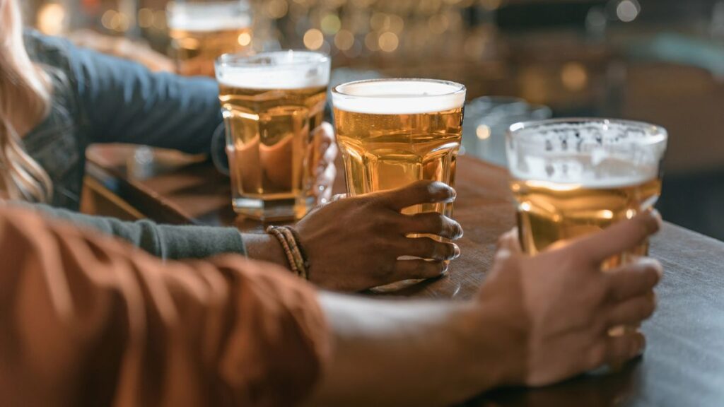 hands holding beers at bar