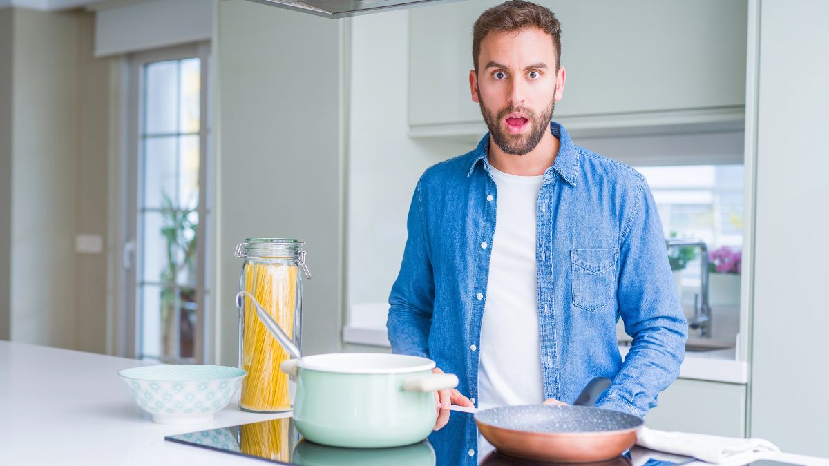 man in kitchen looking shocked with pasta