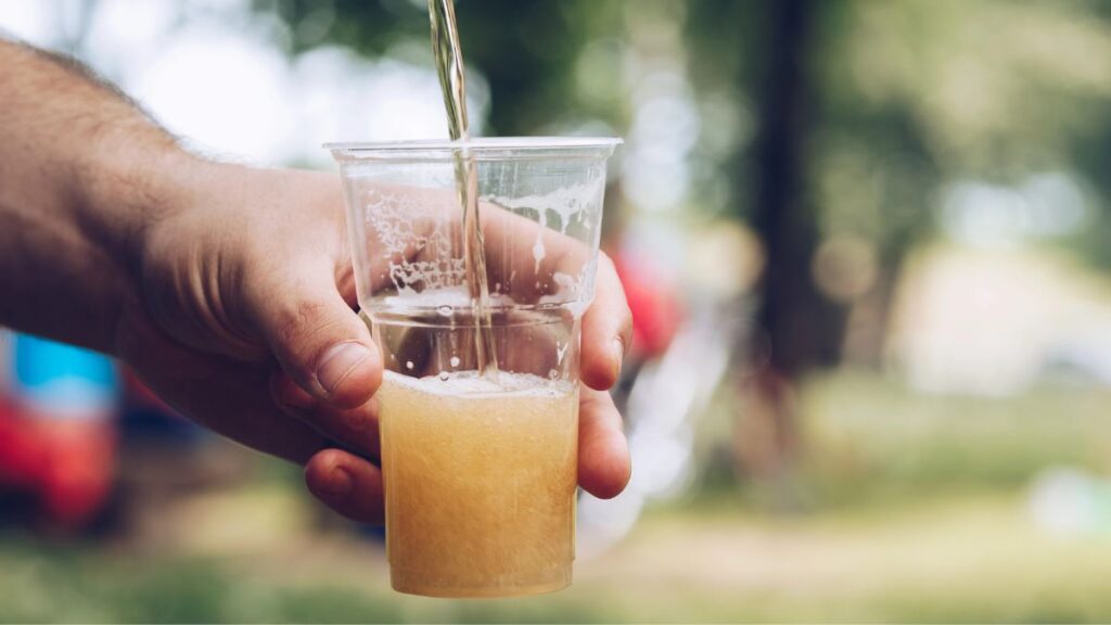 man pouring beer outside