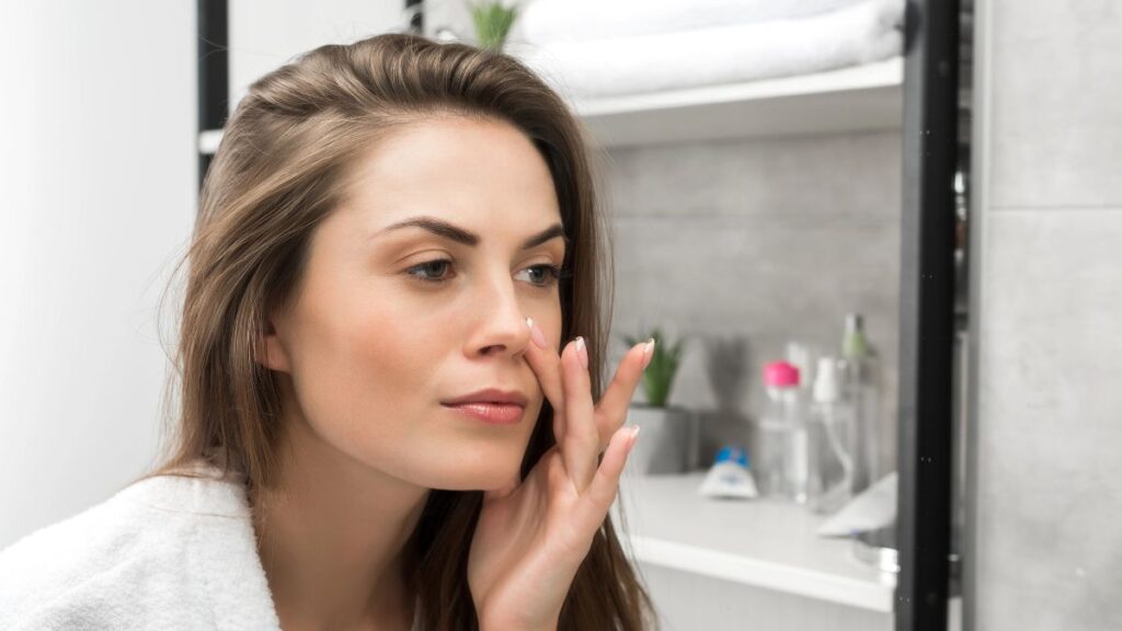 woman checking skin in mirror