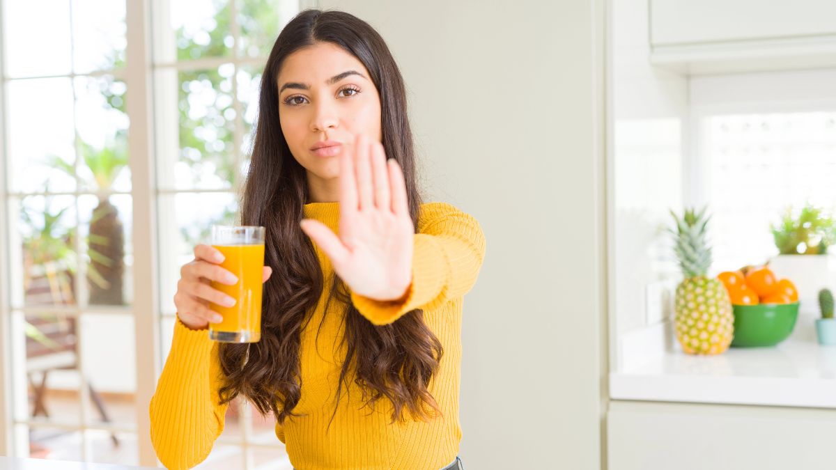 woman in kitchen showing stop with hand and juice