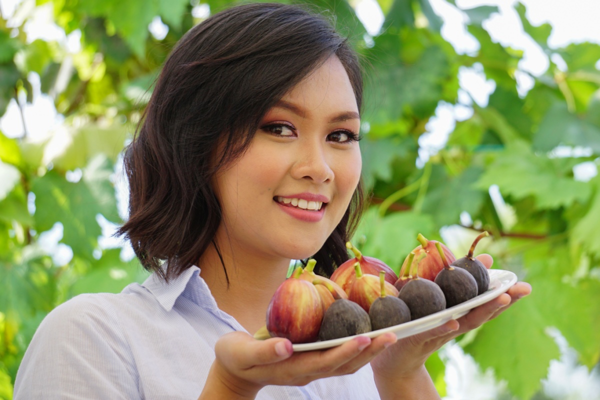 Asian woman holding plate of fresh figs fruit