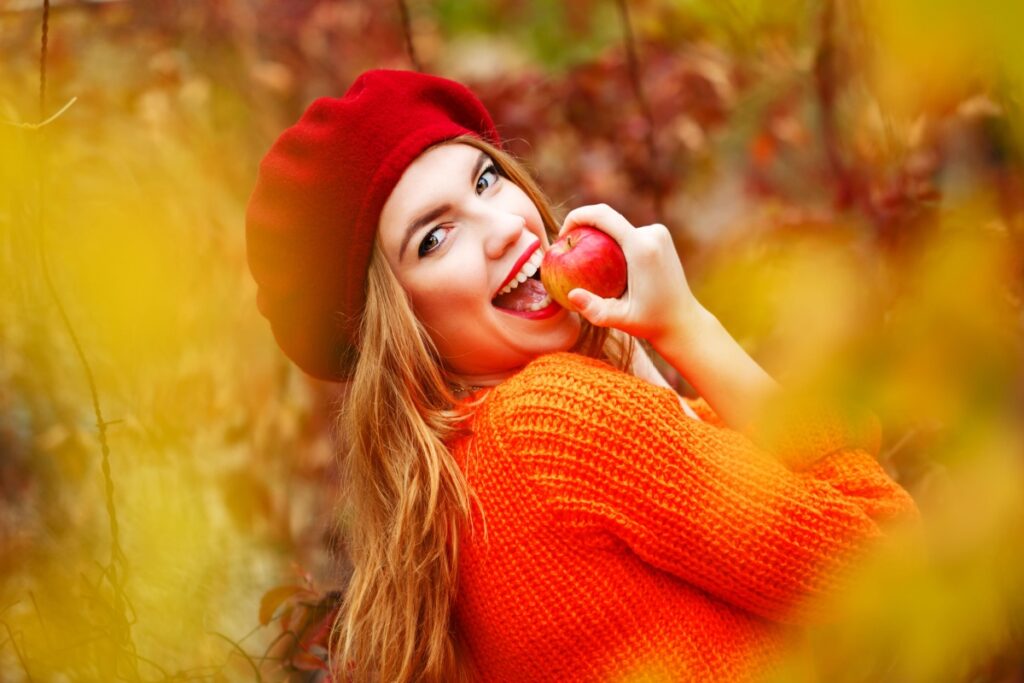 Autumn woman eating apple in fall