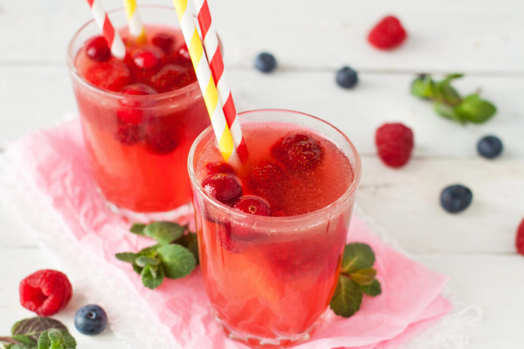 Fresh pink lemonade with raspberry, cranberry, strawberry, apple, lime decorated with mint leaves on white rustic table