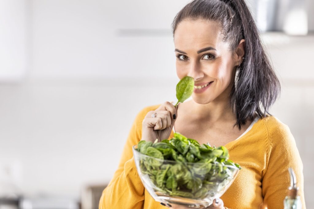 woman holding a bowl full of fresh spinach