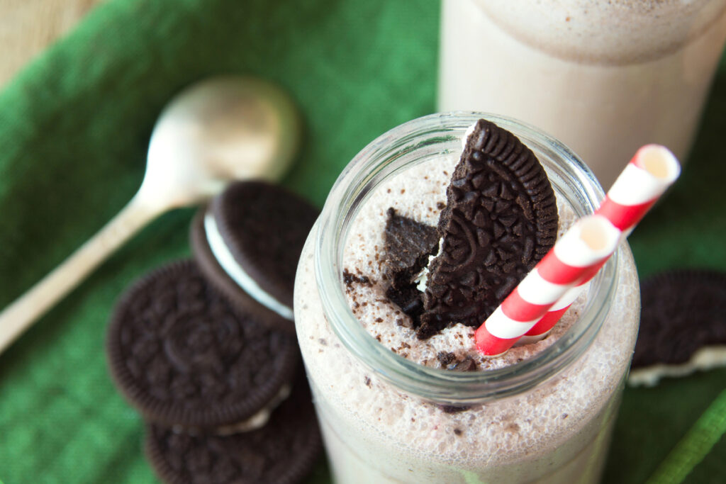 Homemade milkshake (chocolate smoothie) with cookies on rustic wooden table close up