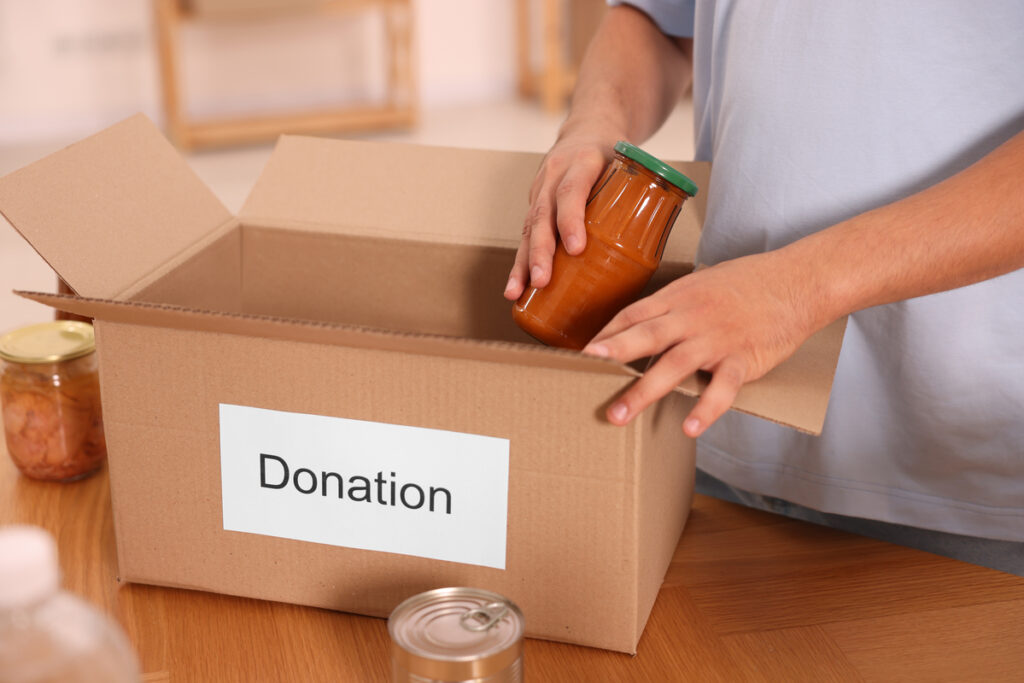 Volunteer packing food products at table indoors, closeup