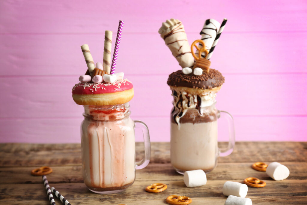 Milkshake, donuts and other sweets in jars on wooden table