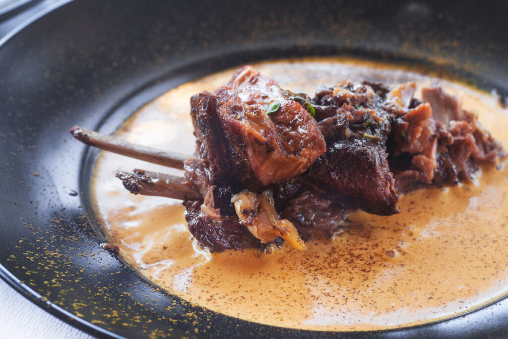 Traditional Naxian slow cooked goat meat with spicy carrot sauce and local herbs (selective focus)