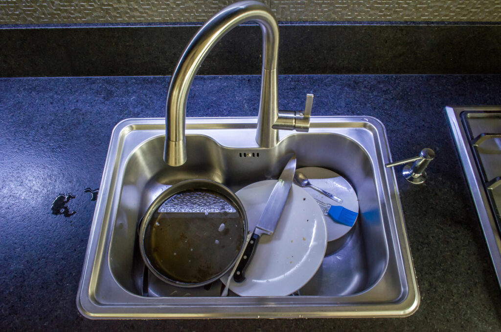 Dishes not washed in the dirty sink, countertop with black granite top.