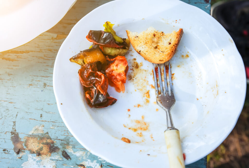 Food leftovers on the plate. Vegetables, meat and bread.