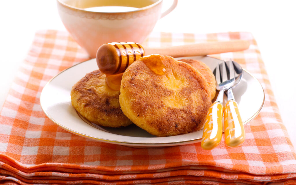 Pumpkin fritters with honey on plate and tea