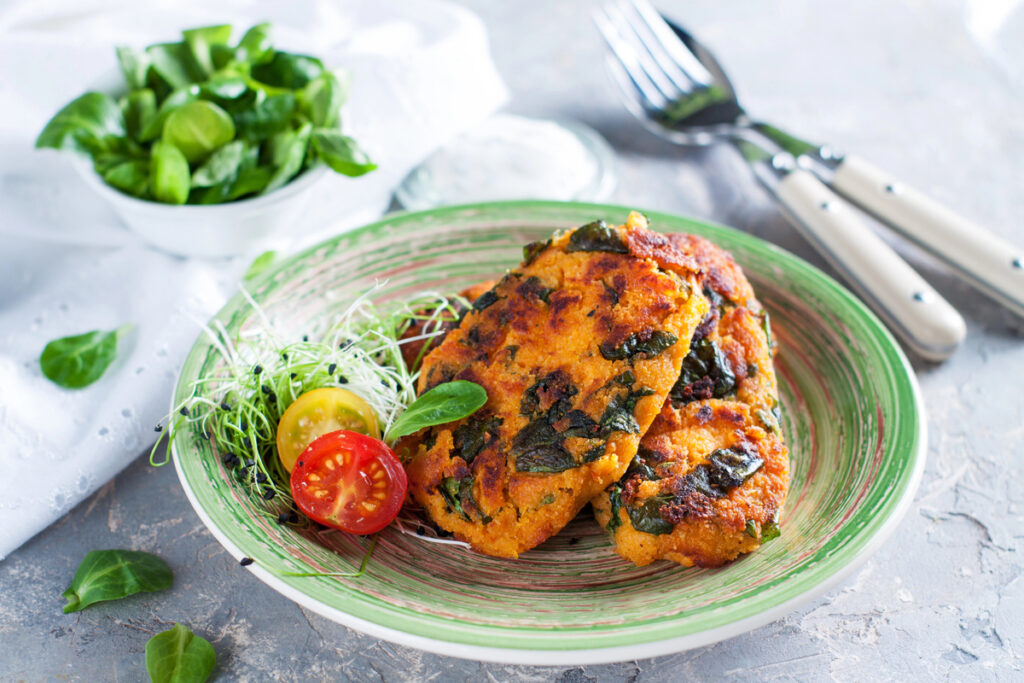 Crispy homemade sweet potato fritters with spinach served with cherry tomatoes