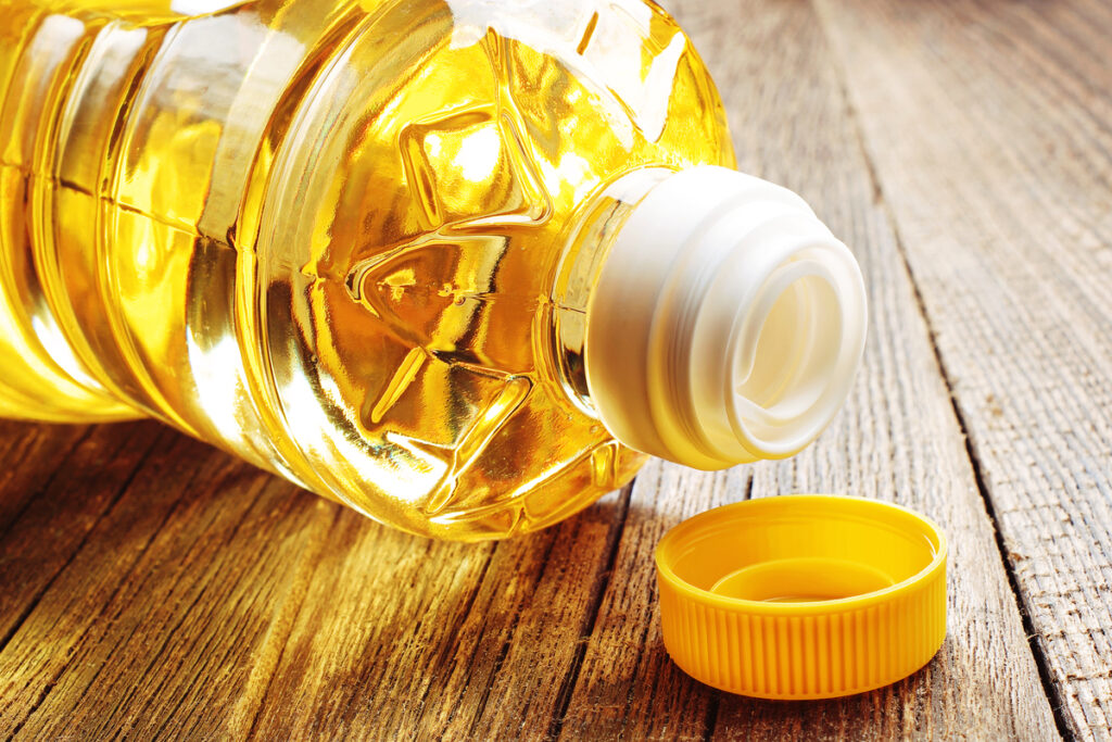 Vegetable oil in plastic bottle closeup on the old wooden table