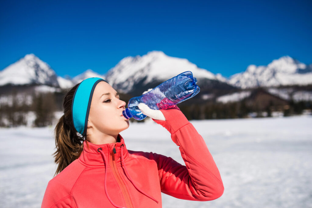 Young woman jogging outside in sunny winter mountains