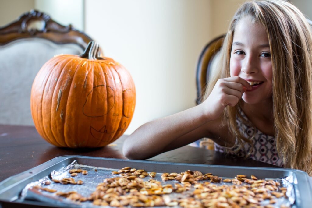 Young girl eating fresh baked pumpkin seeds