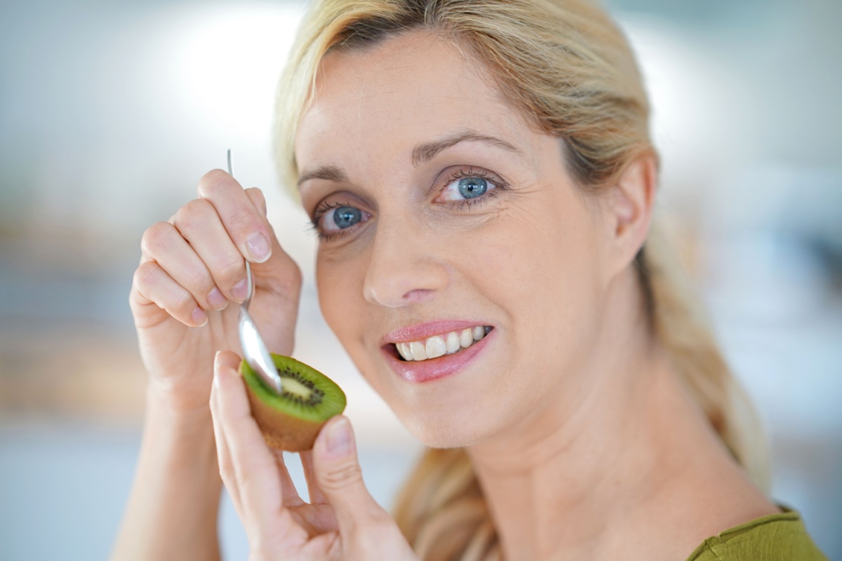 blond woman eating kiwi fruit