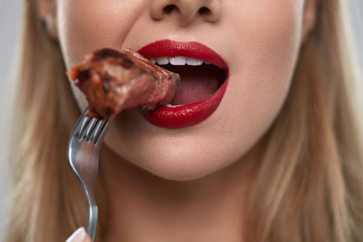 close up of woman red lipstick eating meat on fork