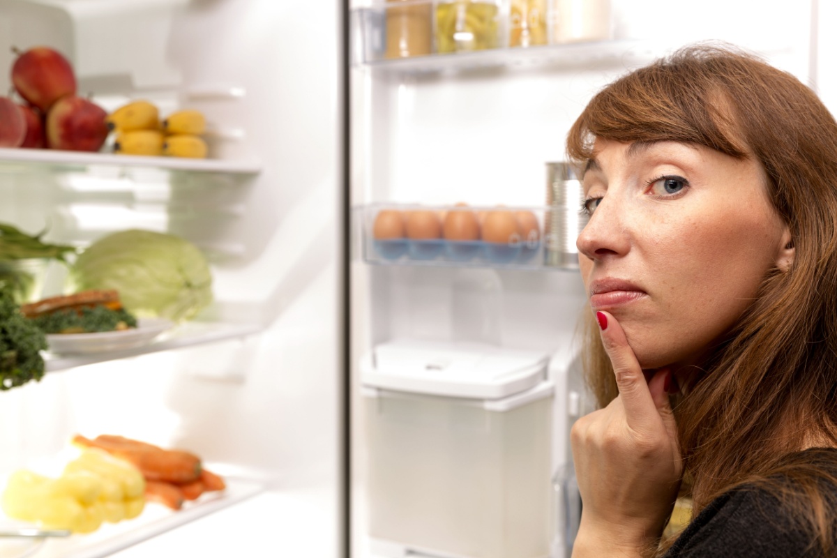 confused woman holding open fridge