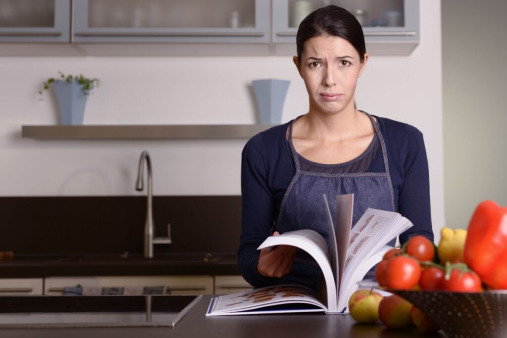 frustrated flipping through cookbook kitchen