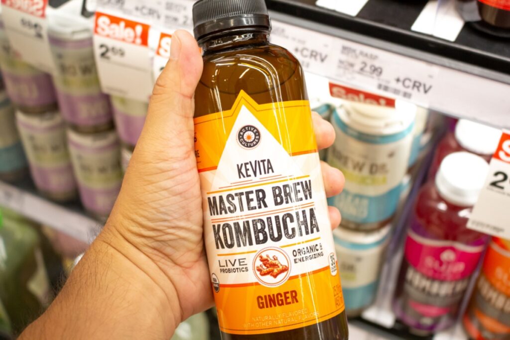 hand holding a bottle of KeVita Kombucha at the grocery store.