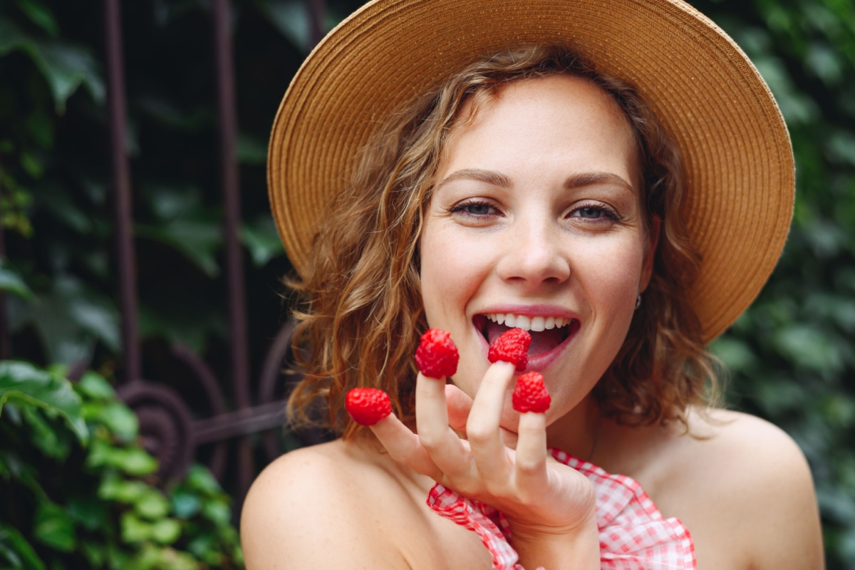 happy woman eating raspberries on fingers