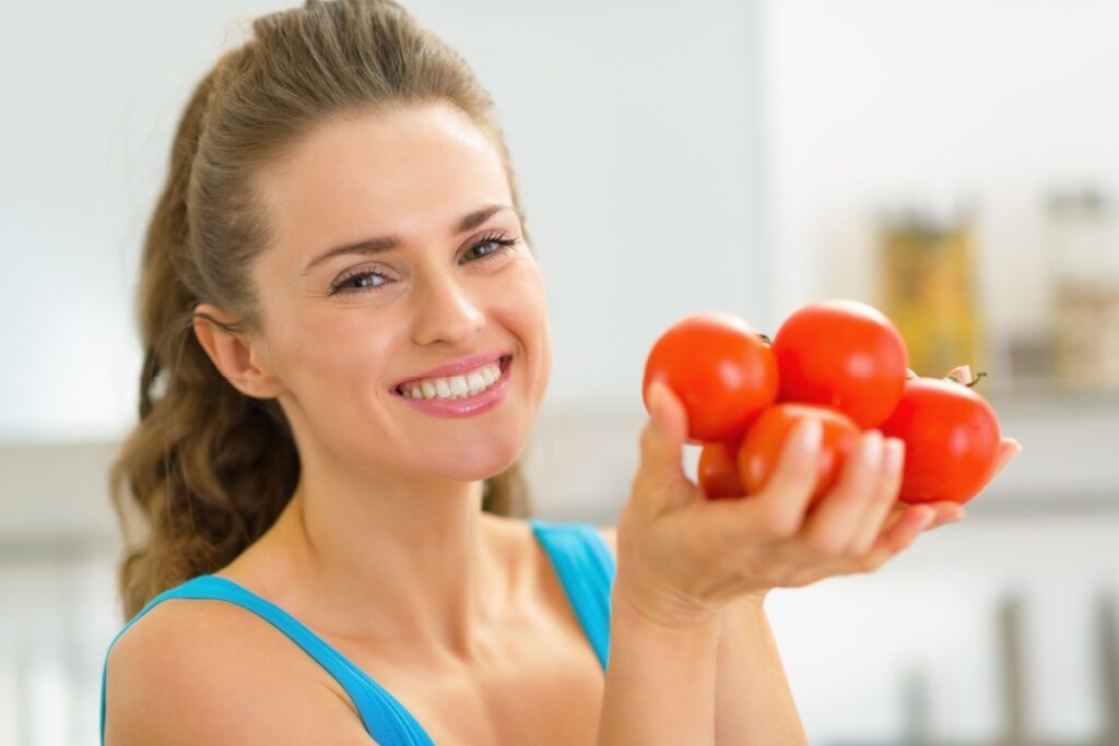 happy young woman showing tomato