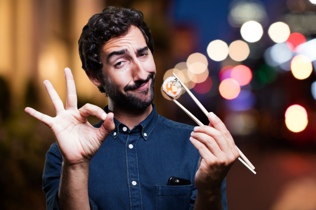 man eating sushi with chopsticks ok sign