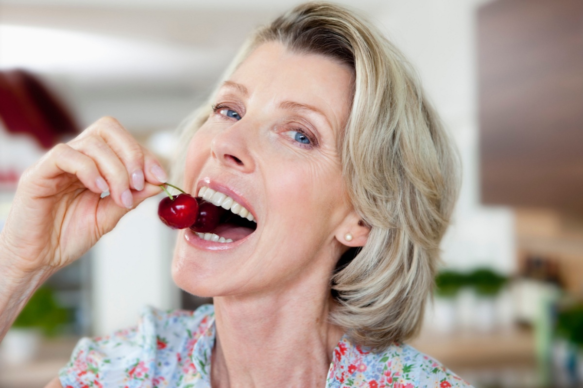 mature senior woman eating cherries fruit