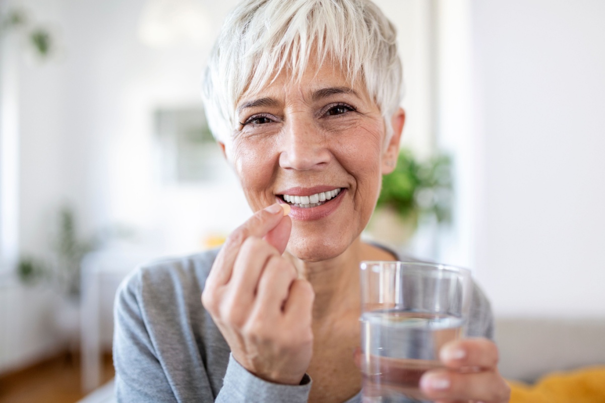 mature senior woman taking pill Vitamin D