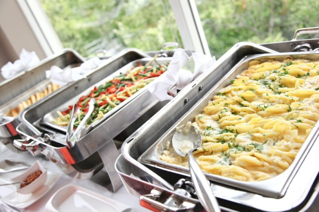 penne pasta and vegetables in stainless steel buffet trays at a brunch party