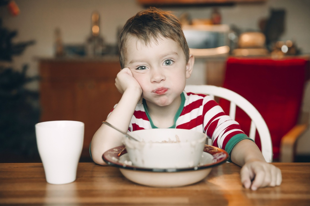 sad boy and a plate of porridge oatmeal