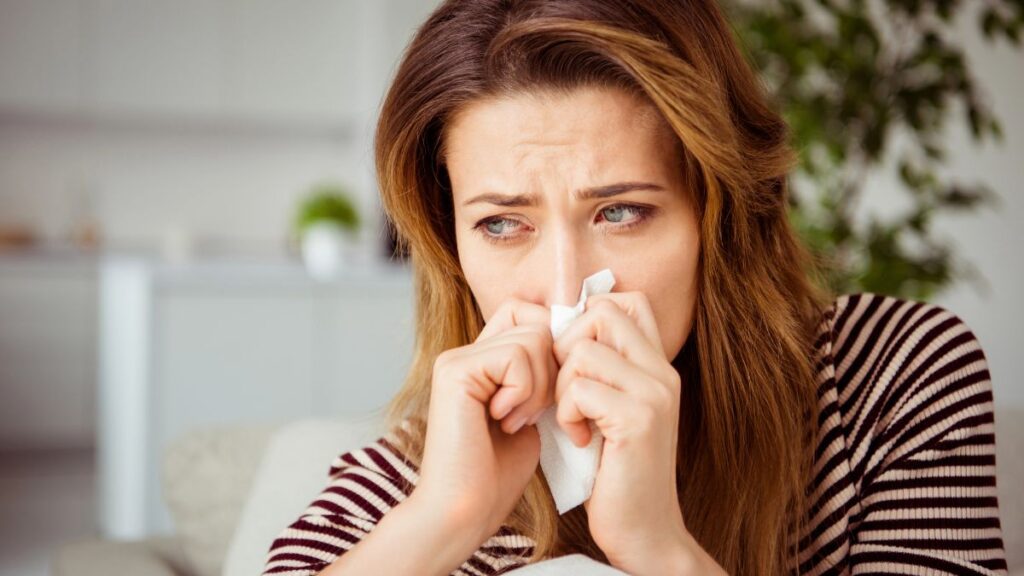 woman blowing nose crying tissue over nose