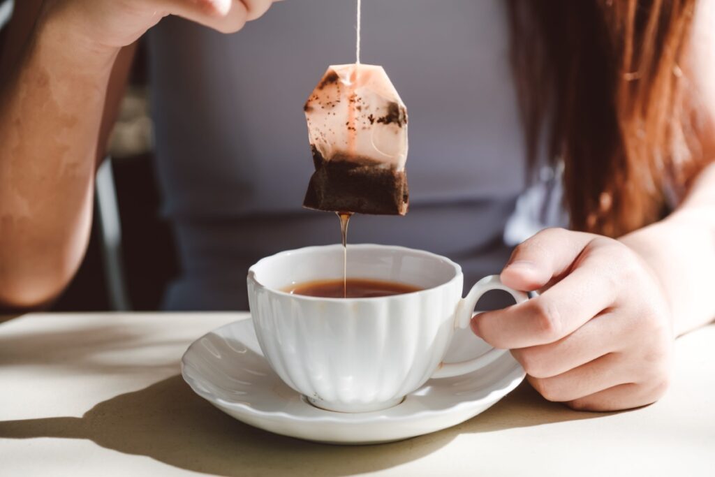 woman dipping tea bag into tea cup